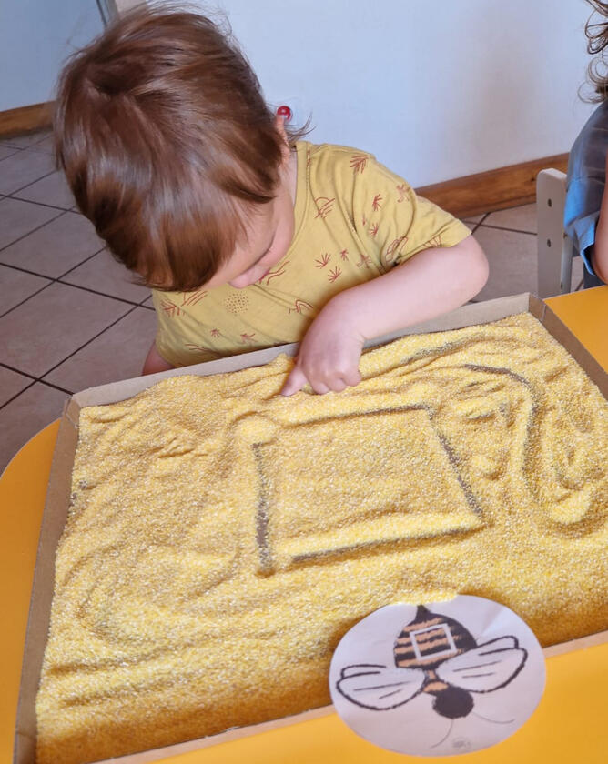 Untitled Дитина малює пальцем по крупі в дитячому садку Mariposa